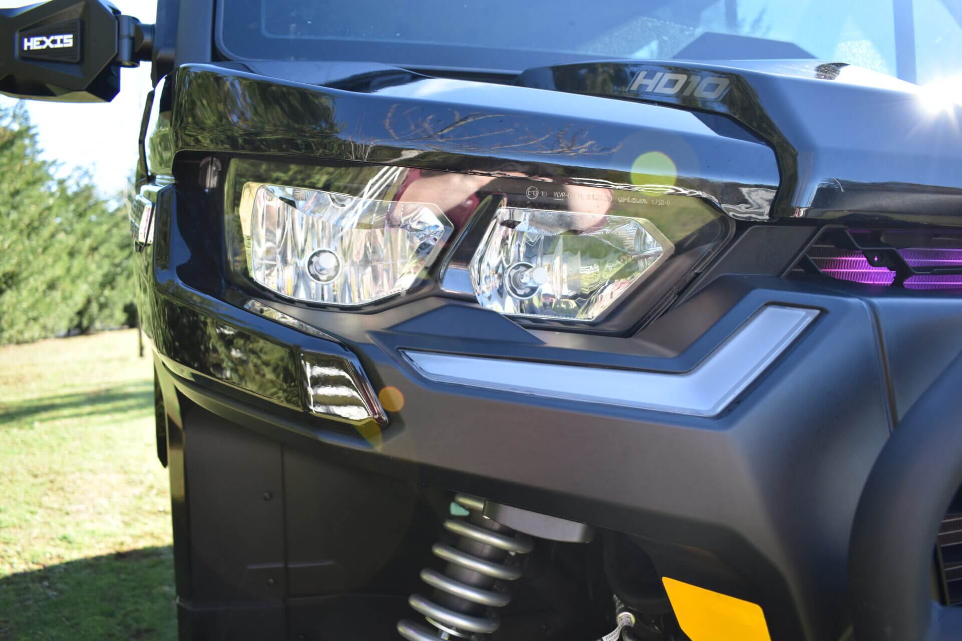 headlight of a vehicle up close with trees in the back.