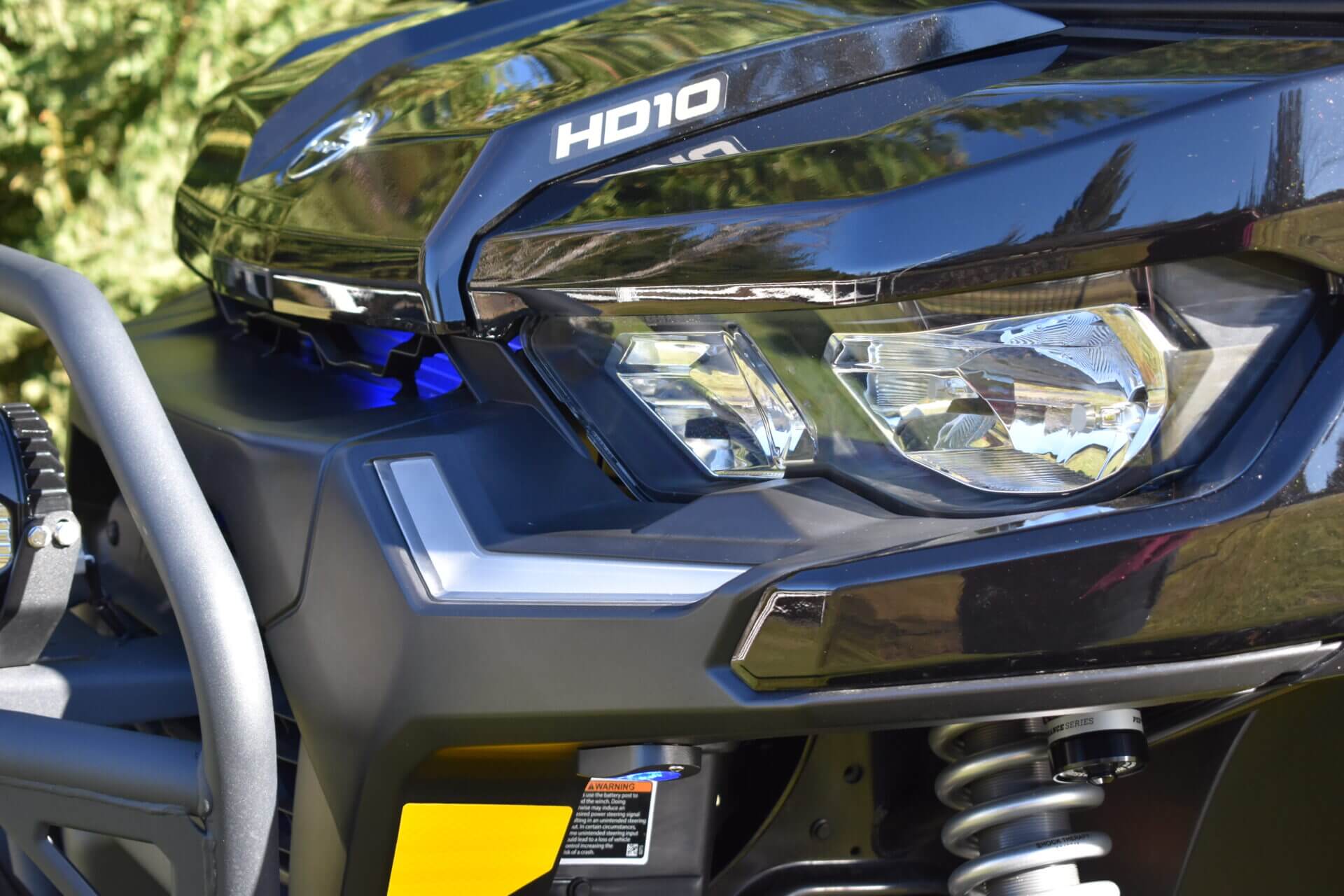 A headlight of a vehicle up close with trees in the back