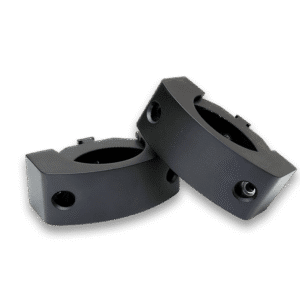 Two black mechanical components on black background.
